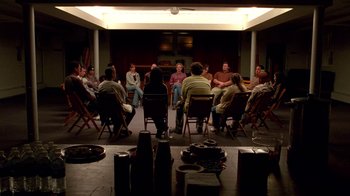 Movie still from “Breaking Bad” (2008), created by Vince Gilligan – A group of people sitting in chairs in a room; Wide shot, High angle