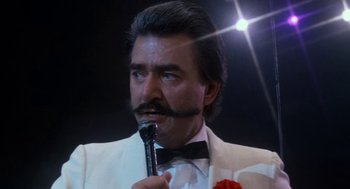 Movie still from “Rocky III” (1982), directed by Sylvester Stallone – A person holding a microphone; Close Up shot, Low angle