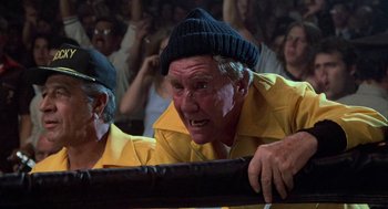 Movie still from “Rocky III” (1982), directed by Sylvester Stallone – An old man wearing a yellow shirt and a black hat; Close Up shot, Low angle