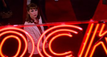Movie still from “Rocky III” (1982), directed by Sylvester Stallone – A woman standing in front of a red neon sign; Medium shot, High angle