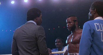 Movie still from “Rocky III” (1982), directed by Sylvester Stallone – A man in a boxing ring talking to a judge; Medium shot, Over the shoulder angle