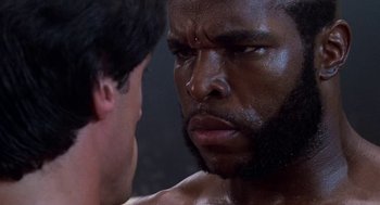 Movie still from “Rocky III” (1982), directed by Sylvester Stallone – A person with a beard looking at another person; Close Up shot, Over the shoulder angle