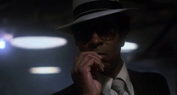 Movie still from “Rocky III” (1982), directed by Sylvester Stallone – A man in a suit and a hat is holding his hand to his face; Close Up shot, Low angle