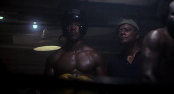Movie still from “Rocky III” (1982), directed by Sylvester Stallone – A man in a boxing ring wearing a helmet; Medium shot, Low angle