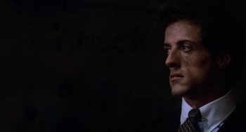 Movie still from “Rocky III” (1982), directed by Sylvester Stallone – A person wearing a suit and tie; Close Up shot, Over the shoulder angle