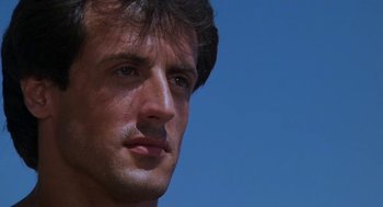 Movie still from “Rocky III” (1982), directed by Sylvester Stallone – A man's face in front of a blue sky; Close Up shot, Low angle