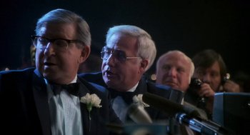 Movie still from “Rocky III” (1982), directed by Sylvester Stallone – A man in a suit and tie with a flower in his lapel; Close Up shot, Over the shoulder angle