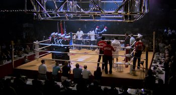 Movie still from “Rocky III” (1982), directed by Sylvester Stallone – A group of people in a boxing ring watching a boxing match; Extreme Wide shot, High angle