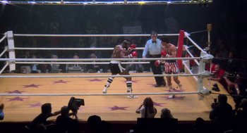 Movie still from “Rocky III” (1982), directed by Sylvester Stallone – Two boxers in a boxing ring during a match; Wide shot, High angle