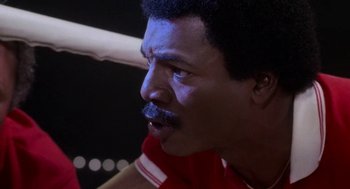 Movie still from “Rocky III” (1982), directed by Sylvester Stallone – A baseball player's face with a baseball bat in the background; Close Up shot, Over the shoulder angle