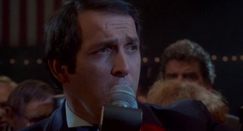 Movie still from “Rocky III” (1982), directed by Sylvester Stallone – A person holding a microphone; Close Up shot, Low angle