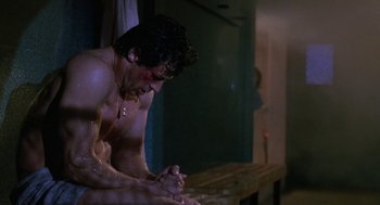 Movie still from “Rocky V” (1990), directed by John G. Avildsen – A man sitting in the shower with his hands clasped together; Medium shot, Low angle