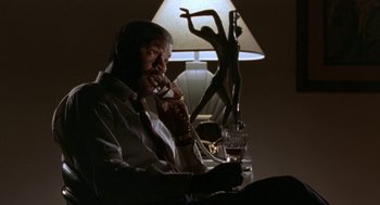 Movie still from “Rocky V” (1990), directed by John G. Avildsen – An older man talking on a phone while sitting at a table; Medium shot, Low angle