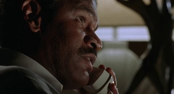 Movie still from “Rocky V” (1990), directed by John G. Avildsen – An older man talking on a phone while sitting in a car; Close Up shot, Low angle