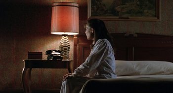 Movie still from “Rocky V” (1990), directed by John G. Avildsen – A woman sitting on the edge of a bed in front of a lamp; Medium shot, High angle