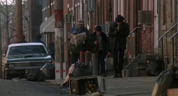 Movie still from “Rocky V” (1990), directed by John G. Avildsen – A group of people standing on the side of the street; Wide shot, High angle