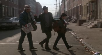 Movie still from “Rocky V” (1990), directed by John G. Avildsen – A group of people walking down a street; Wide shot, Low angle