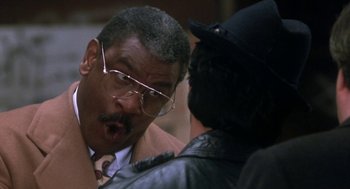 Movie still from “Rocky V” (1990), directed by John G. Avildsen – A man in a suit and tie talking to another man in a leather jacket; Close Up shot, Over the shoulder angle