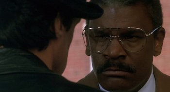 Movie still from “Rocky V” (1990), directed by John G. Avildsen – A man with glasses is looking at another man with glasses on; Close Up shot, Over the shoulder angle