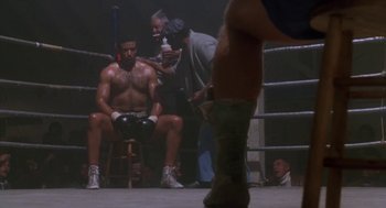 Movie still from “Rocky V” (1990), directed by John G. Avildsen – A man sitting on a chair in a boxing ring; Wide shot, Low angle