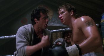Movie still from “Rocky V” (1990), directed by John G. Avildsen – Two men in a boxing ring with one of the men holding a boxing mitts; Medium shot, Low angle