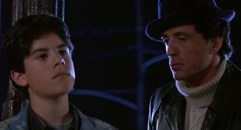 Movie still from “Rocky V” (1990), directed by John G. Avildsen – A man and a woman standing next to each other in the dark; Close Up shot, Over the shoulder angle
