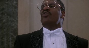 Movie still from “Rocky V” (1990), directed by John G. Avildsen – A person wearing a suit and glasses; Close Up shot, Low angle