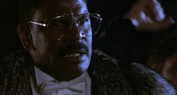Movie still from “Rocky V” (1990), directed by John G. Avildsen – An older man wearing glasses and a bow tie and a fur coat; Close Up shot, Low angle