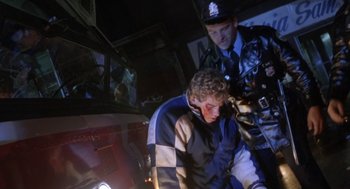 Movie still from “Rocky V” (1990), directed by John G. Avildsen – A police officer is helping a man who is bleeding from his face; Medium shot, Low angle