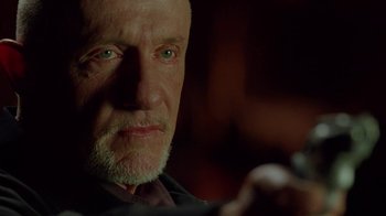 Movie still from “Breaking Bad” (2008), created by Vince Gilligan – An older man looking at the camera while holding a cell phone; Close Up shot, Low angle