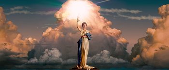 A statue of a woman holding a sword in front of a cloud filled sky