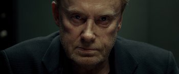 Movie still from “Salt” (2010), directed by Phillip Noyce – An older man with a beard and a mustache; Close Up shot, Over the shoulder angle