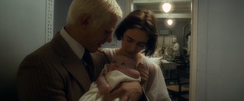 Movie still from “Salt” (2010), directed by Phillip Noyce – A man and a woman holding a baby in a hospital room; Close Up shot, High angle