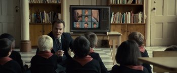 Movie still from “Salt” (2010), directed by Phillip Noyce – A group of people sitting in front of a television; Medium shot, Over the shoulder angle