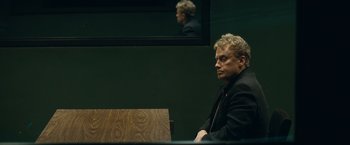 Movie still from “Salt” (2010), directed by Phillip Noyce – A man sitting at a table in front of a television; Close Up shot, Over the shoulder angle