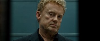 Movie still from “Salt” (2010), directed by Phillip Noyce – A man with blonde hair and a black shirt; Close Up shot, Low angle