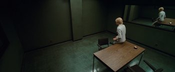 Movie still from “Salt” (2010), directed by Phillip Noyce – A person sitting at a table in a room; Wide shot, High angle