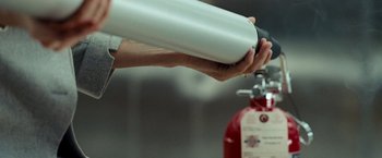 Movie still from “Salt” (2010), directed by Phillip Noyce – A person holding a fire extinguisher in their hand; Extreme Close Up shot, Low angle
