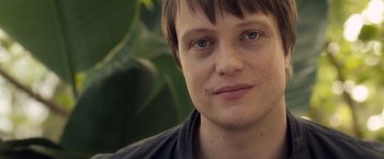Movie still from “Salt” (2010), directed by Phillip Noyce – A person's face with a plant in the background; Close Up shot, Over the shoulder angle