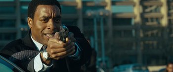 Movie still from “Salt” (2010), directed by Phillip Noyce – A man holding a gun while wearing a suit and tie; Close Up shot, Over the shoulder angle