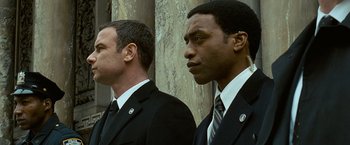 Movie still from “Salt” (2010), directed by Phillip Noyce – A couple of men standing next to each other in suits; Close Up shot, Low angle