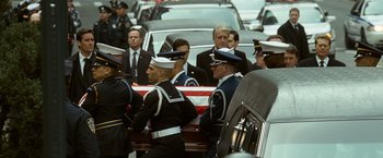 Movie still from “Salt” (2010), directed by Phillip Noyce – A group of men standing next to an american flag draped casket; Wide shot, Low angle