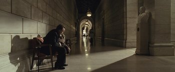 Movie still from “Salt” (2010), directed by Phillip Noyce – A man sitting on a chair next to a woman in a hallway; Extreme Wide shot, High angle