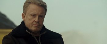 Movie still from “Salt” (2010), directed by Phillip Noyce – An older man in a black jacket looks at the camera; Close Up shot, Over the shoulder angle