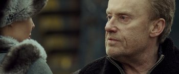 Movie still from “Salt” (2010), directed by Phillip Noyce – An older man with a goatee looking off into the distance; Close Up shot, Over the shoulder angle