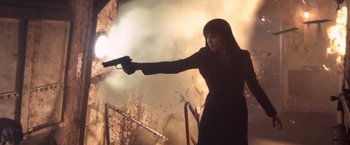Movie still from “Salt” (2010), directed by Phillip Noyce – A woman holding a gun in front of an exploding wall; Medium shot, Low angle