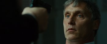 Movie still from “Salt” (2010), directed by Phillip Noyce – A man with a gun pointed at another man's face; Close Up shot, Over the shoulder angle