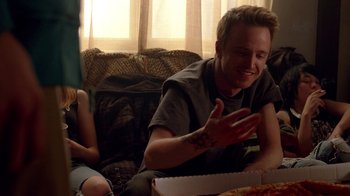 Movie still from “Breaking Bad” (2008), created by Vince Gilligan – A man sitting on a couch eating a pizza; Medium shot, Over the shoulder angle