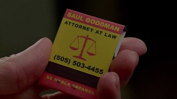 Movie still from “Breaking Bad” (2008), created by Vince Gilligan – A person holding a matchbook that reads " saul goodman attorney at law "; Extreme Close Up shot, Overhead angle