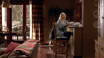 Movie still from “Breaking Bad” (2008), created by Vince Gilligan – A woman sitting at a table in a living room; Wide shot, High angle